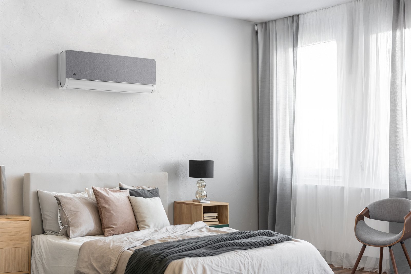 Weiß-graues Split-Klimagerät an der Schlafzimmerwand über einem Bett in hellem Wohnambiente